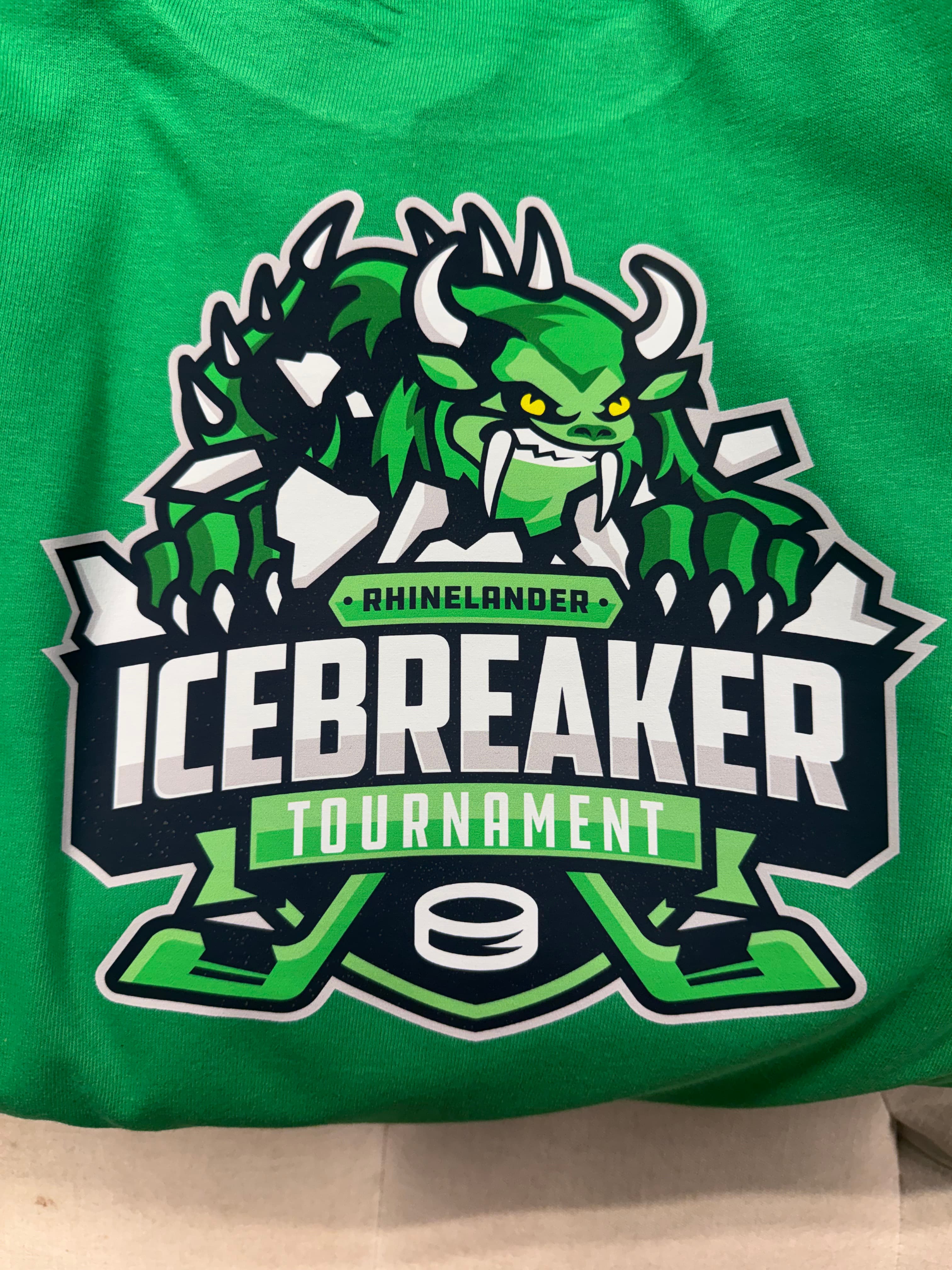 Rhinelander Icebreaker Tournament logo featuring a green Hodag monster, hockey puck, and sticks.